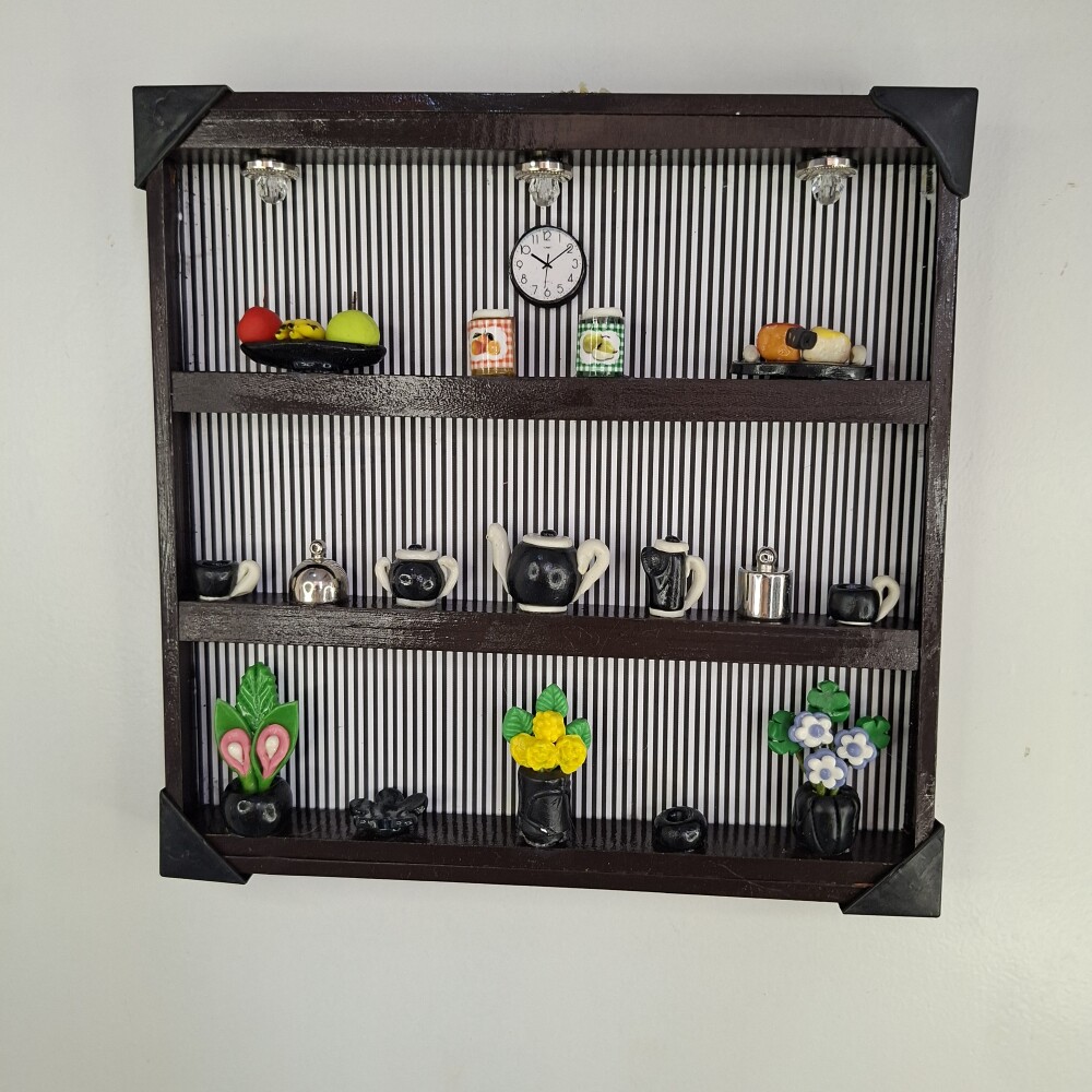 Quadro de ferro preto com fundo listrado decorado com miniaturas