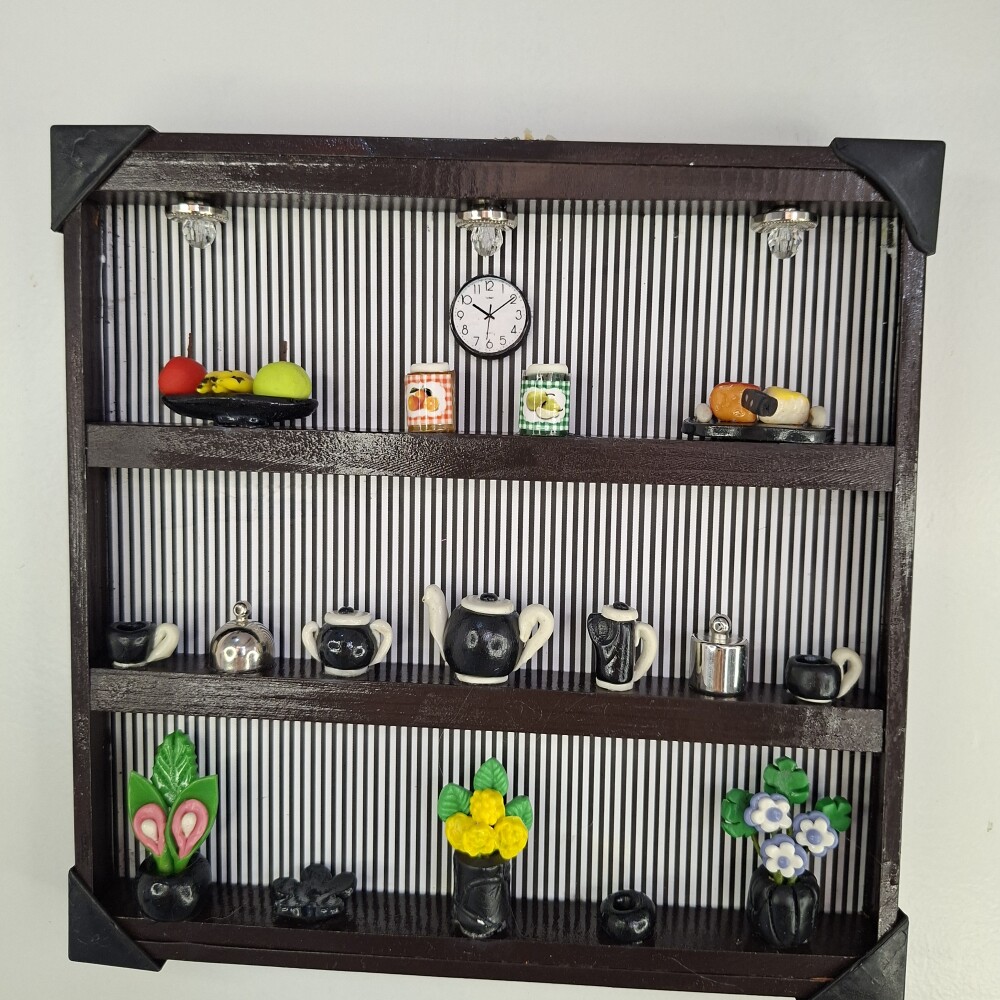 Quadro de ferro preto com fundo listrado decorado com miniaturas