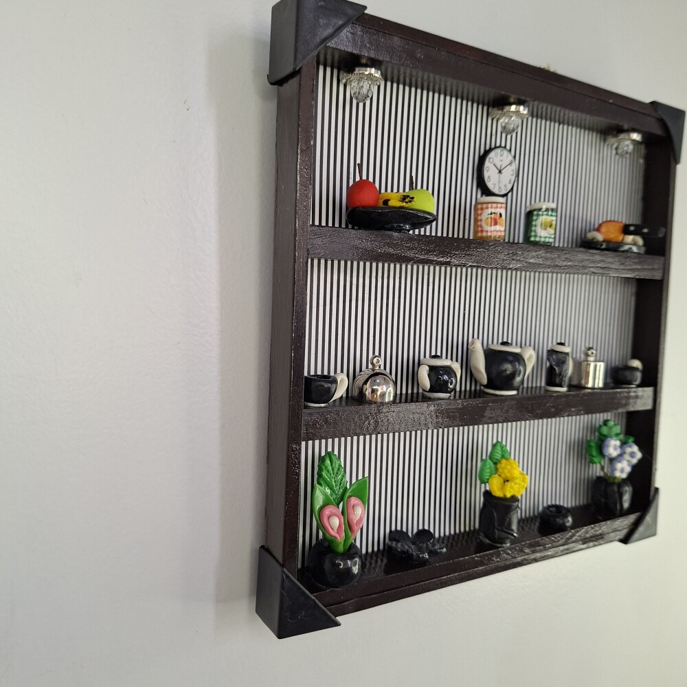 Quadro de ferro preto com fundo listrado decorado com miniaturas