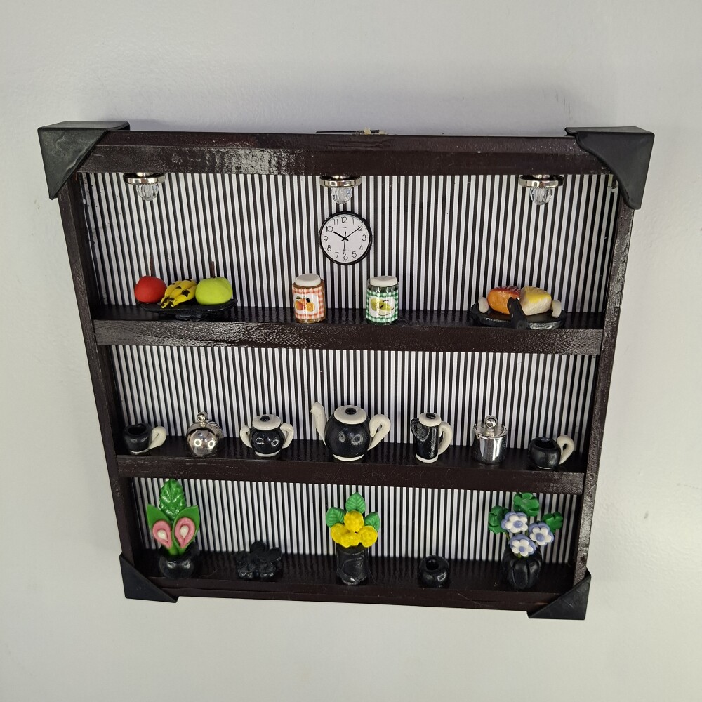 Quadro de ferro preto com fundo listrado decorado com miniaturas