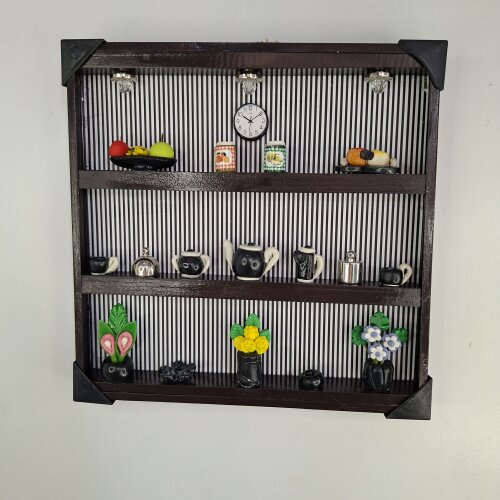 Quadro de ferro preto com fundo listrado decorado com miniaturas