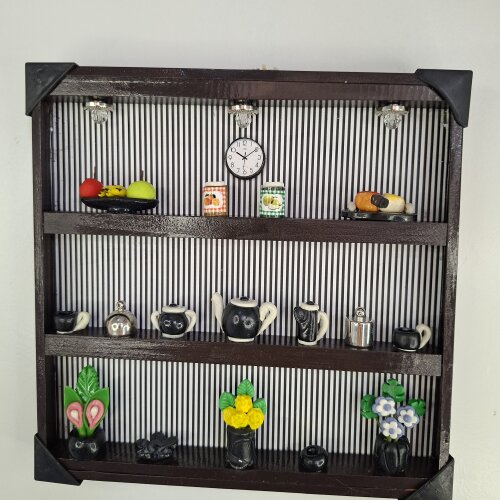 Quadro de ferro preto com fundo listrado decorado com miniaturas
